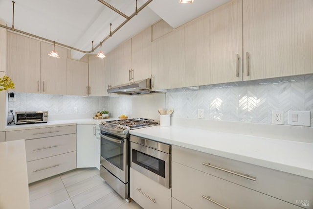 kitchen featuring backsplash, light brown cabinetry, gas stove, light countertops, and under cabinet range hood