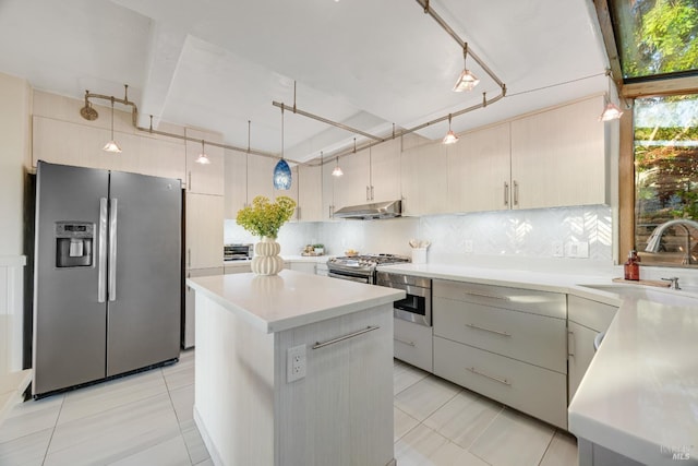 kitchen with backsplash, appliances with stainless steel finishes, a sink, light countertops, and light tile patterned flooring