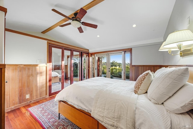 bedroom featuring french doors, access to exterior, wood finished floors, a wainscoted wall, and vaulted ceiling with beams