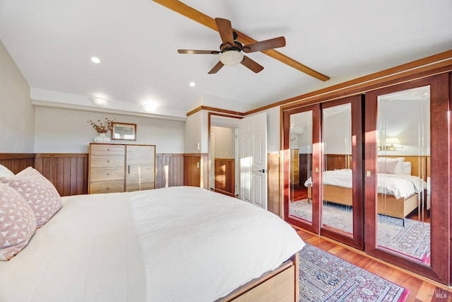 bedroom featuring wood finished floors, lofted ceiling, ceiling fan, recessed lighting, and a wainscoted wall