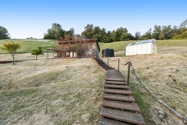 view of yard featuring a storage unit, an outbuilding, a rural view, and stairway