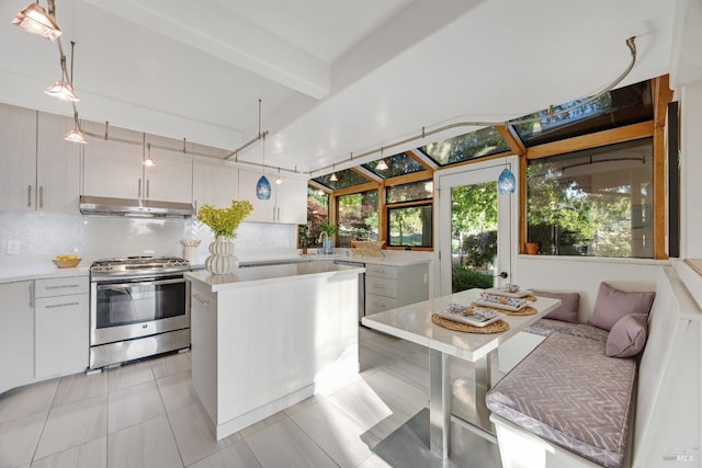 kitchen with under cabinet range hood, light countertops, backsplash, and stainless steel gas stove