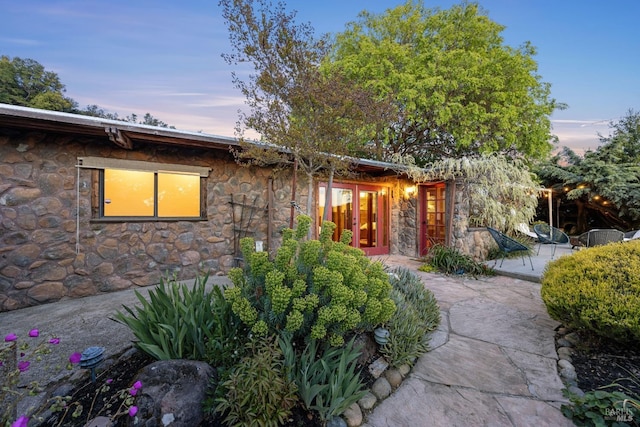 view of front of house featuring a patio area, french doors, and stone siding