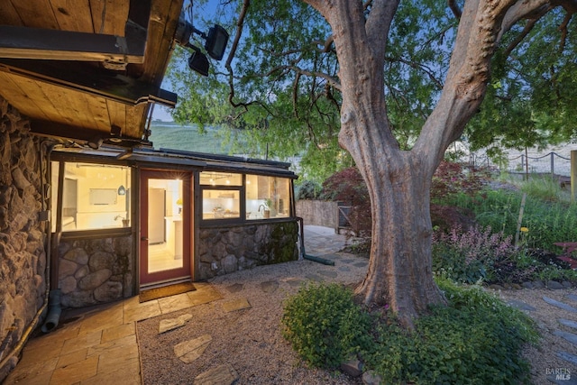 view of exterior entry featuring fence and stone siding