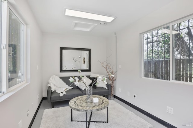 living area featuring baseboards and attic access
