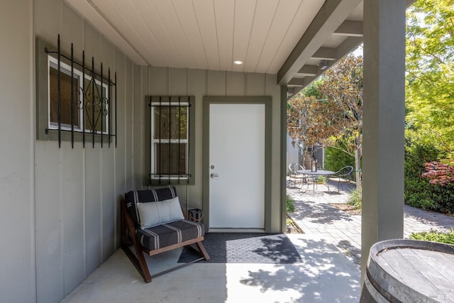 entrance to property with board and batten siding, a patio, and outdoor dining area