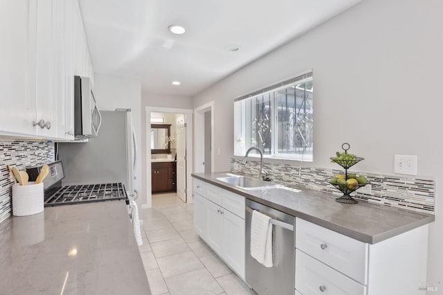 kitchen featuring a sink, decorative backsplash, appliances with stainless steel finishes, and white cabinets