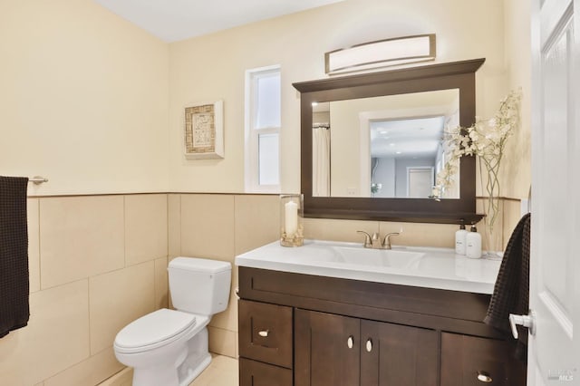 bathroom with vanity, a wainscoted wall, toilet, and tile walls