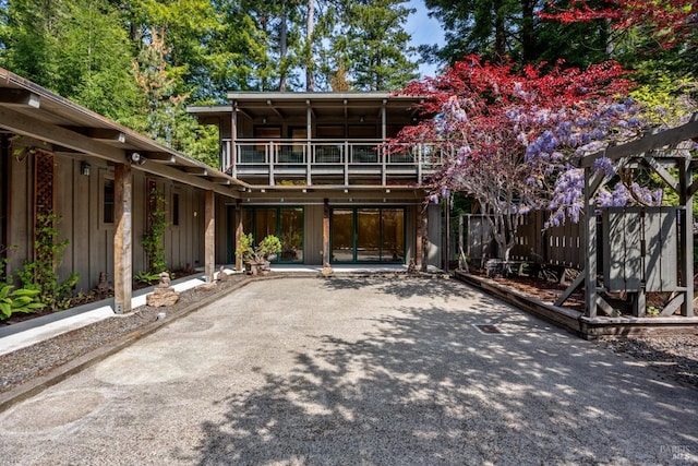 rear view of property featuring fence, board and batten siding, and a balcony