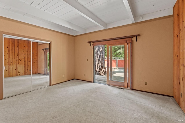 spare room featuring baseboards, carpet flooring, beam ceiling, and visible vents