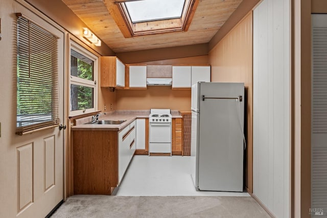 kitchen with white appliances, light countertops, under cabinet range hood, white cabinets, and a sink
