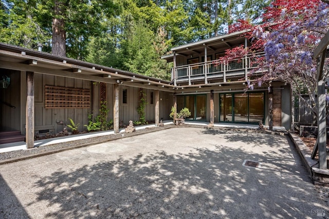 back of property featuring driveway, a balcony, and a patio area
