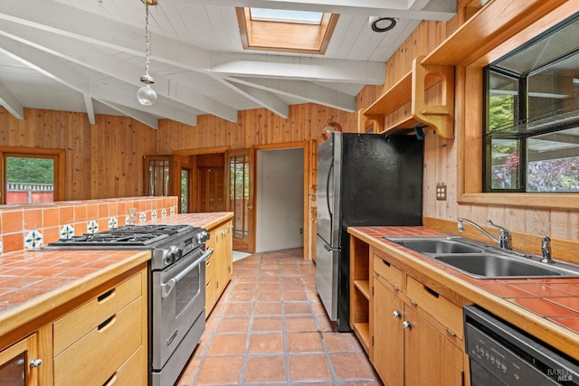 kitchen featuring a sink, tile counters, wood walls, stainless steel appliances, and beamed ceiling