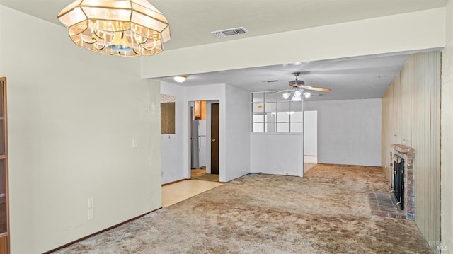 unfurnished living room featuring visible vents, carpet flooring, ceiling fan with notable chandelier, and a fireplace