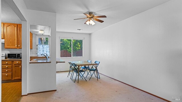 dining room with baseboards, light colored carpet, and ceiling fan