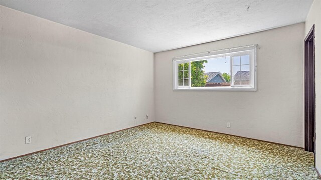 carpeted empty room featuring baseboards