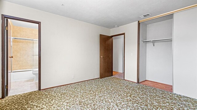 unfurnished bedroom featuring carpet floors, visible vents, ensuite bathroom, and a closet