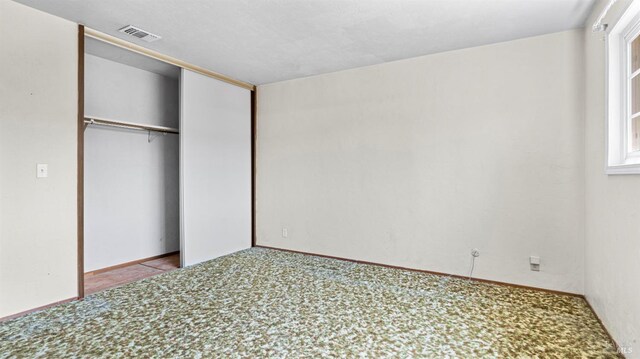 unfurnished bedroom with baseboards, visible vents, carpet, and a closet