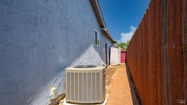 view of property exterior featuring fence, central AC unit, and stucco siding
