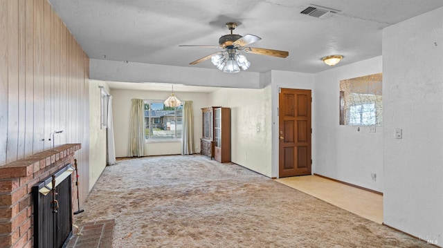 unfurnished living room featuring carpet, a ceiling fan, a brick fireplace, and visible vents