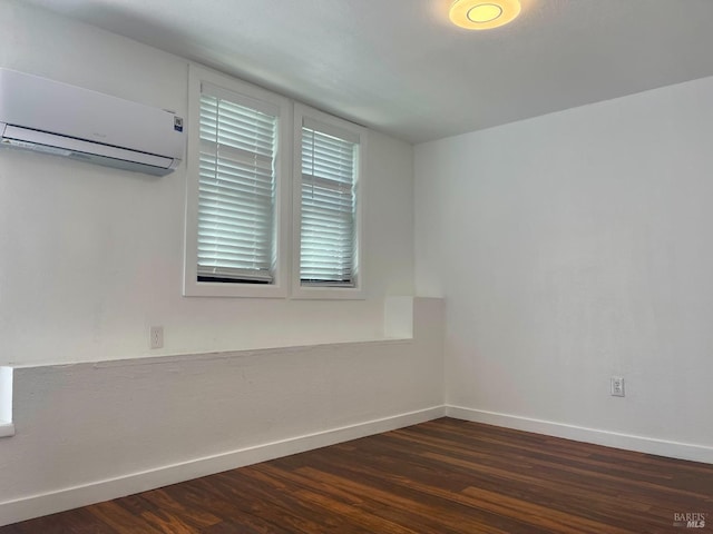 empty room featuring baseboards, an AC wall unit, and dark wood-style flooring