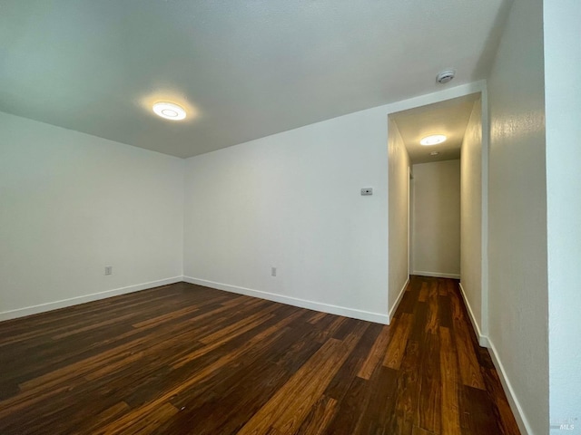 spare room with baseboards and dark wood-style floors