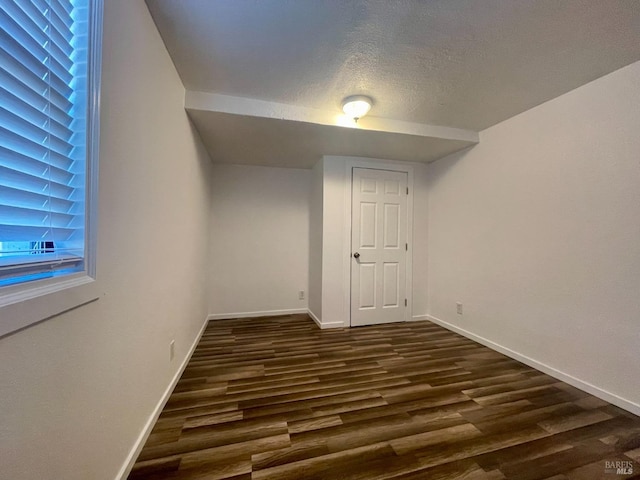 interior space with baseboards, a textured ceiling, and dark wood-style flooring