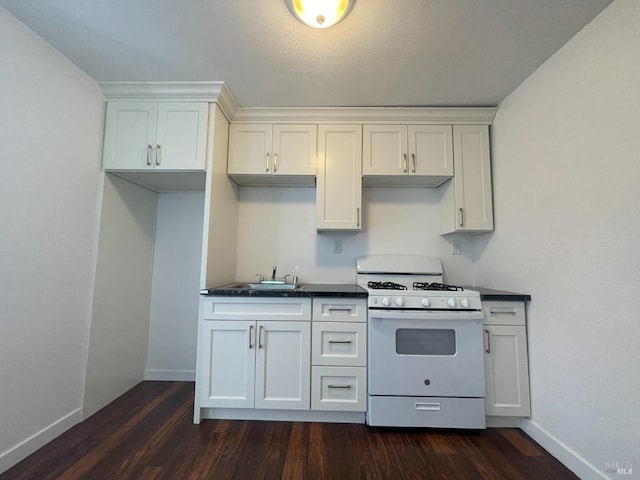 kitchen featuring dark countertops, baseboards, white range with gas cooktop, and dark wood-style floors