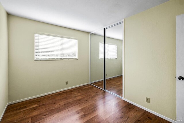 unfurnished bedroom featuring a closet, baseboards, and wood finished floors