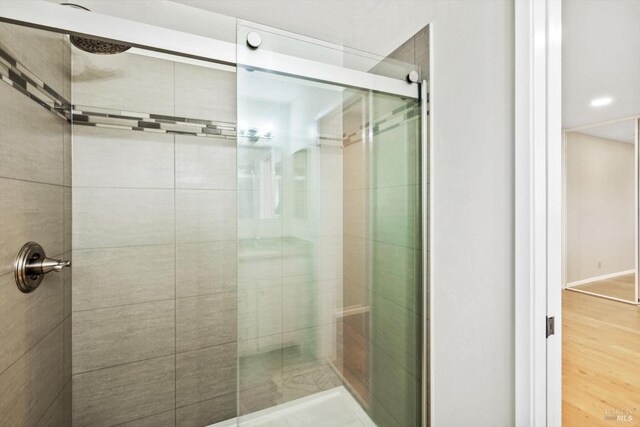 full bathroom with wood finished floors and a shower stall