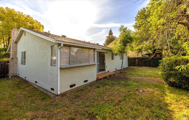 exterior space featuring stucco siding, fence, a yard, and crawl space