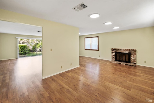 unfurnished living room with baseboards, visible vents, plenty of natural light, and wood finished floors