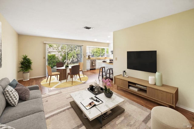 living room with recessed lighting, baseboards, light wood-type flooring, and visible vents