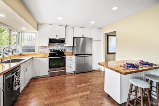 kitchen with a sink, tasteful backsplash, stainless steel appliances, and butcher block counters