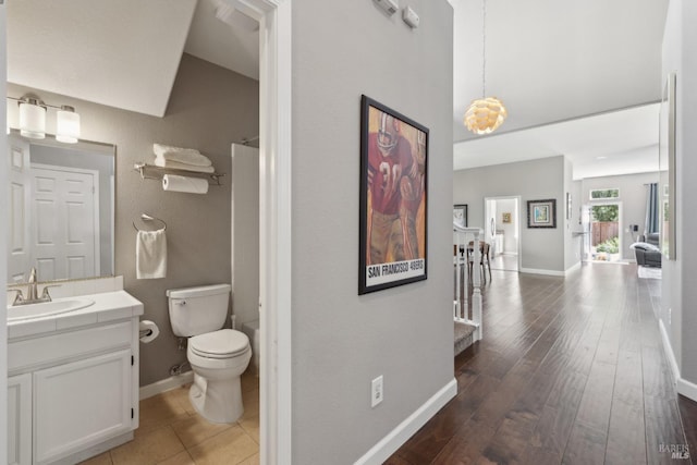 full bathroom with vaulted ceiling, wood finished floors, vanity, baseboards, and toilet