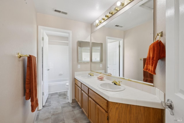 full bath with visible vents, a sink, double vanity, and toilet