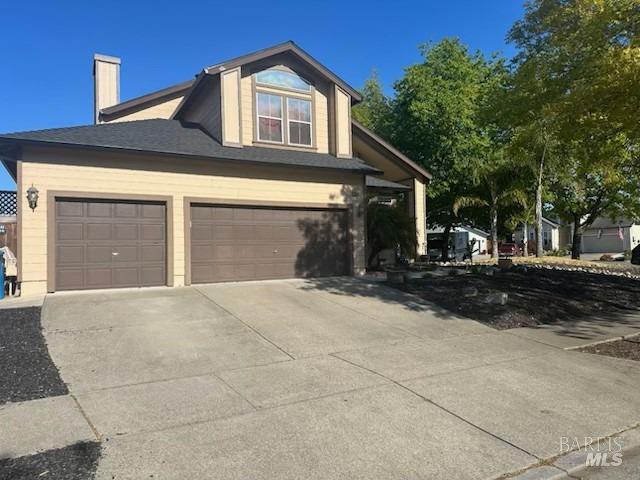 view of front of property with a chimney, an attached garage, and driveway