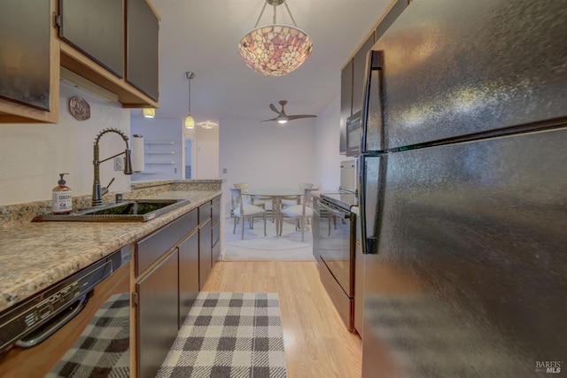 kitchen featuring ceiling fan, decorative light fixtures, light wood-type flooring, a sink, and black appliances
