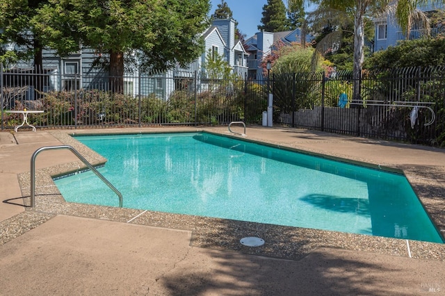 community pool with fence, a patio area, and a residential view