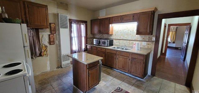 kitchen featuring a sink, white appliances, a heating unit, a center island, and decorative backsplash