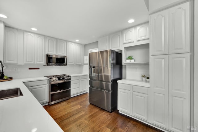 kitchen with appliances with stainless steel finishes, a sink, light countertops, white cabinetry, and recessed lighting