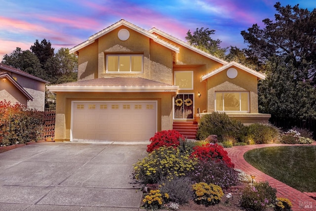 view of front facade featuring an attached garage, driveway, and stucco siding