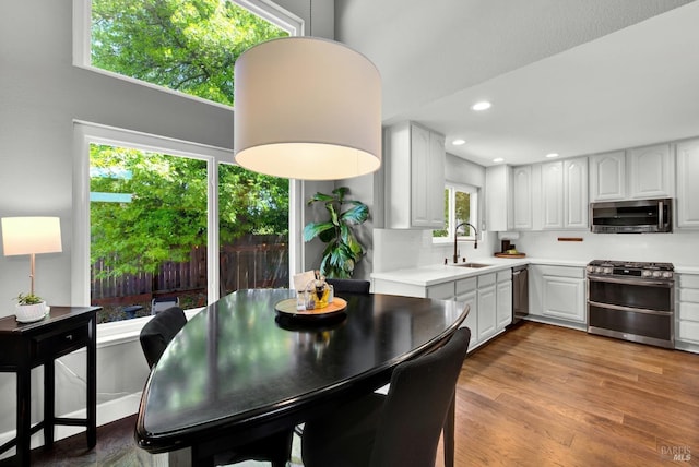 kitchen featuring appliances with stainless steel finishes, a sink, light countertops, white cabinets, and wood finished floors