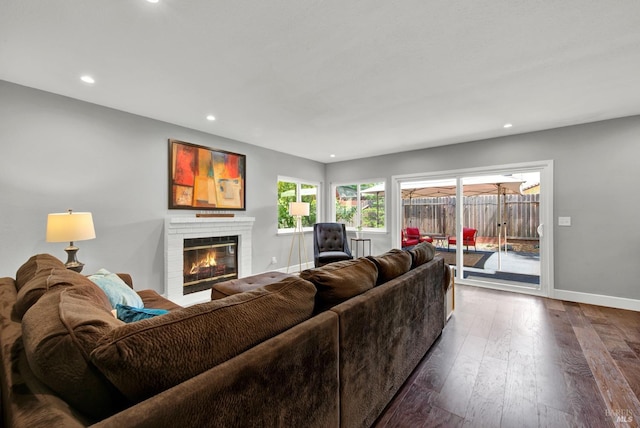 living area featuring recessed lighting, baseboards, a fireplace, and dark wood-type flooring