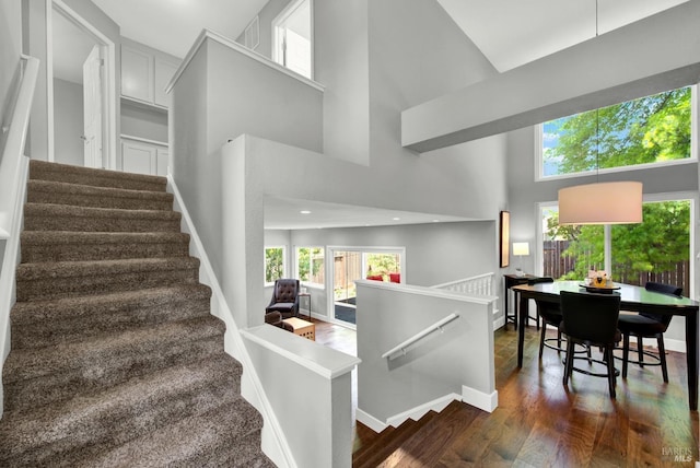 stairs with recessed lighting, a high ceiling, a healthy amount of sunlight, and wood finished floors