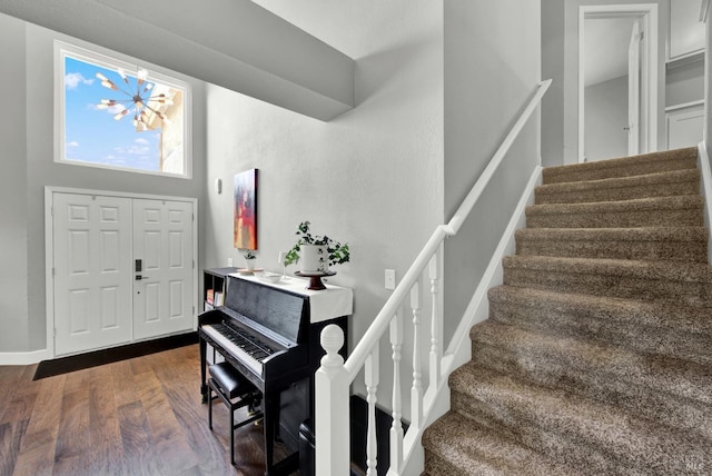 foyer entrance with stairway, dark wood-style flooring, a chandelier, and baseboards