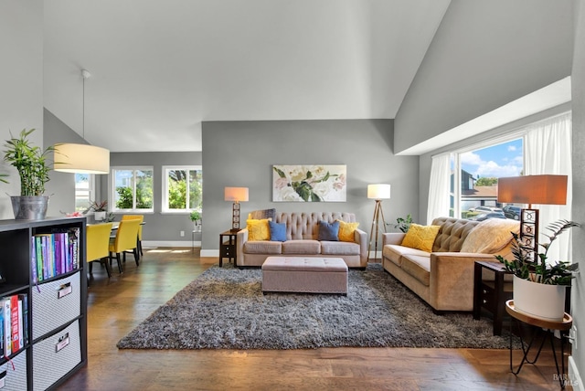 living room featuring baseboards, high vaulted ceiling, and wood finished floors