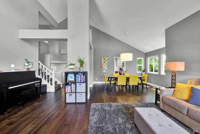 living area featuring wood finished floors, high vaulted ceiling, stairs, and baseboards
