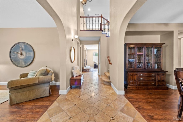 tiled foyer entrance with arched walkways, baseboards, and a towering ceiling