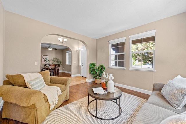 living area with arched walkways, baseboards, a wealth of natural light, and wood finished floors